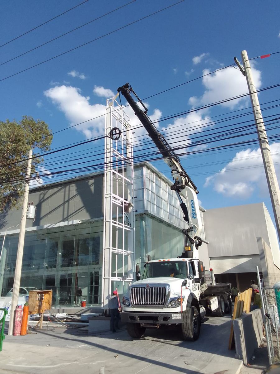 Grúa instalando estructura en agencia automotriz