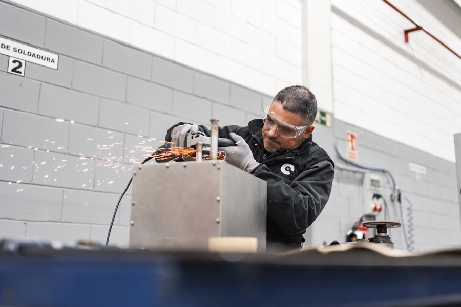Técnico puliendo bordes metálicos con esmeriladora, chispas en taller