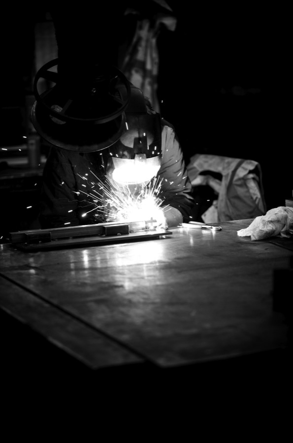 Soldador trabajando con chispas en taller industrial